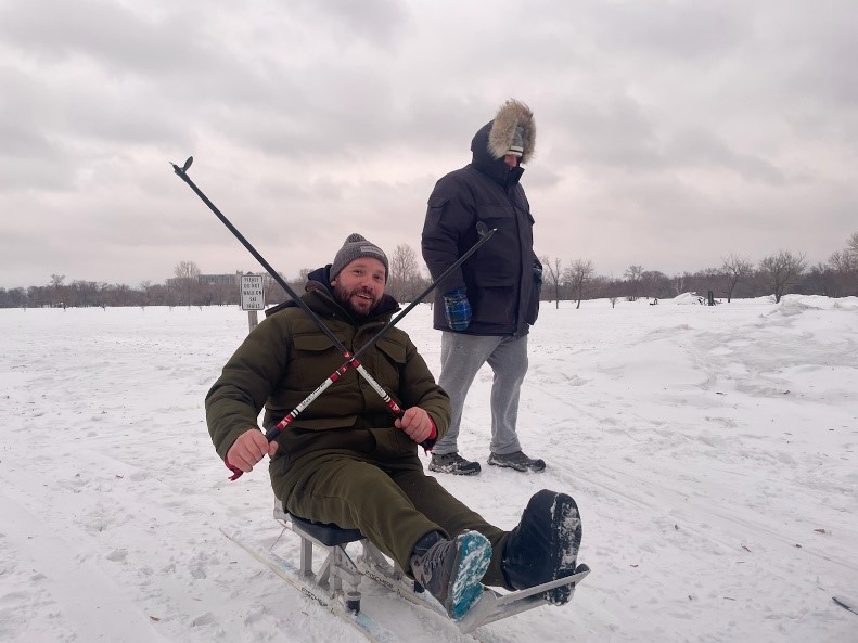 A man using a sit skis device outside in the winter.