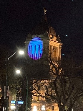 The Manitoba Legislative Building lit in purple and blue.
